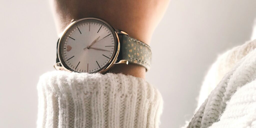 Gros plan d'une montre ornant le poignet d'une femme vêtue de blanc. Photo concept symbolisant l'attente.