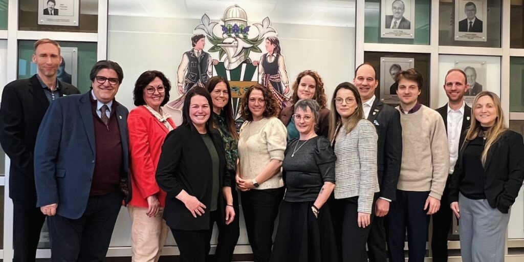 Une douzaine de personnes professionnelles posent en souriant dans une salle officielle de l'UQTR.
